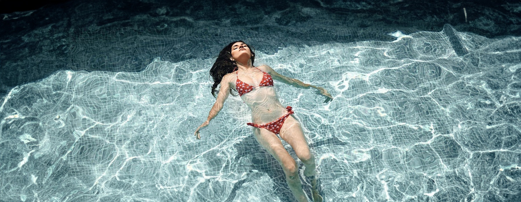 woman floats on her back in swimming pool