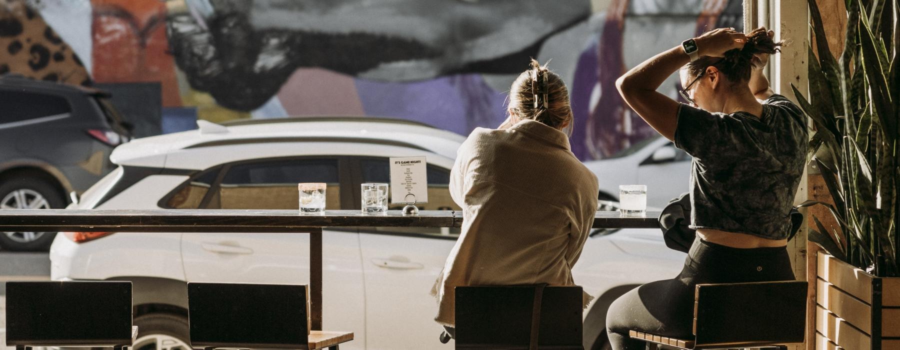 a couple of people sitting at a table looking at a large painting